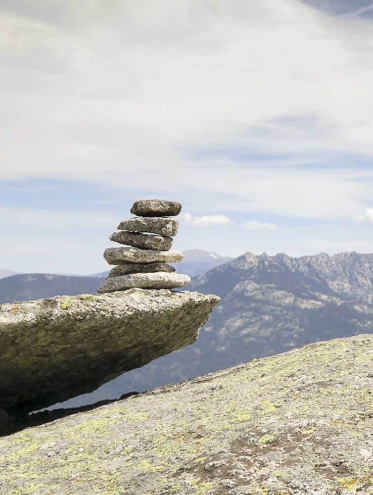 un grupo de rocas apiladas en el medio natural en la pedriza indicando como hito del senderismo como deporte de montaña en madrid