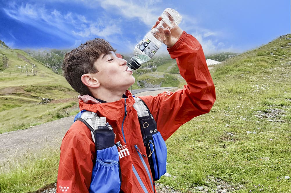 un corredor de montaña en la montaña tomando agua dando hidratacion a su cuerpo