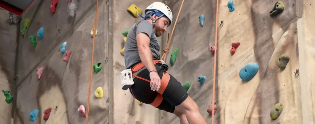 una escaladora escalando haciendo el curso de bautismo de escalada en el rocodromo roc30